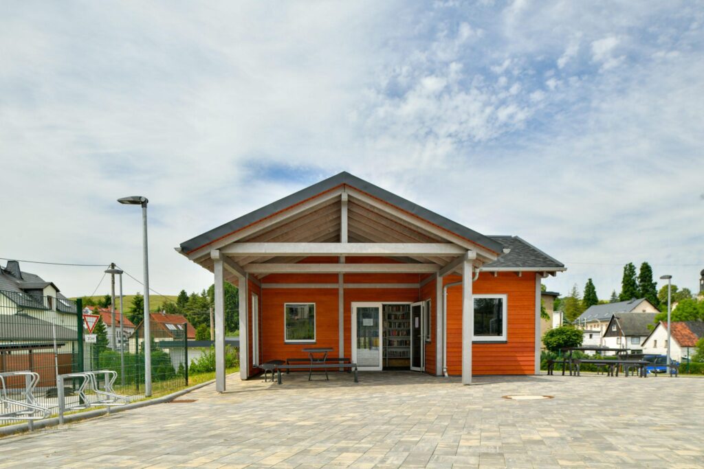 Neues oder saniertes Gebäude (Vereinshaus/Funktionsgebäude) mit gepflastertem Vorplatz.