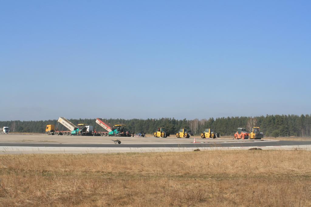 Die Luftaufnahme zeigt den beeindruckenden Umfang der Asphaltierungsarbeiten im Driving Center Groß-Dölln (Brandenburg). Zahlreiche Baumaschinen sind im Einsatz, um die ehemaligen Runways und Flugbetriebsflächen in moderne, hochleistungsfähige Fahrübungsflächen und Teststrecken zu verwandeln. 