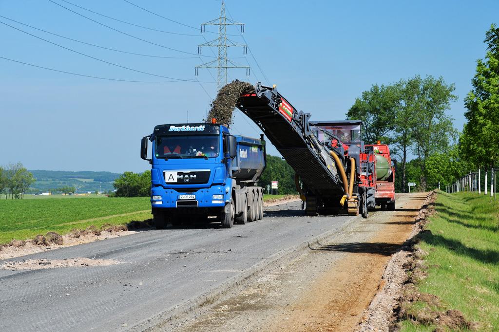 Straßenfräse (Kaltfräse) entfernt alte Asphaltschicht und lädt Material auf LKW.
