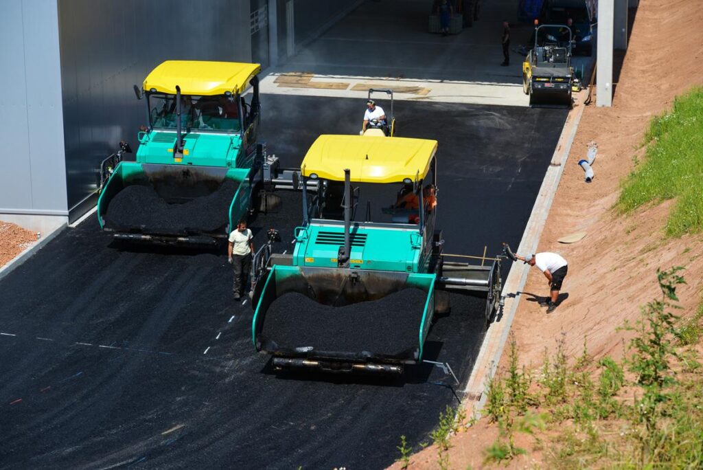 Zwei Straßenfertiger im parallelen Einsatz beim Asphalteinbau für eine besonders breite Fahrbahn oder Fläche.