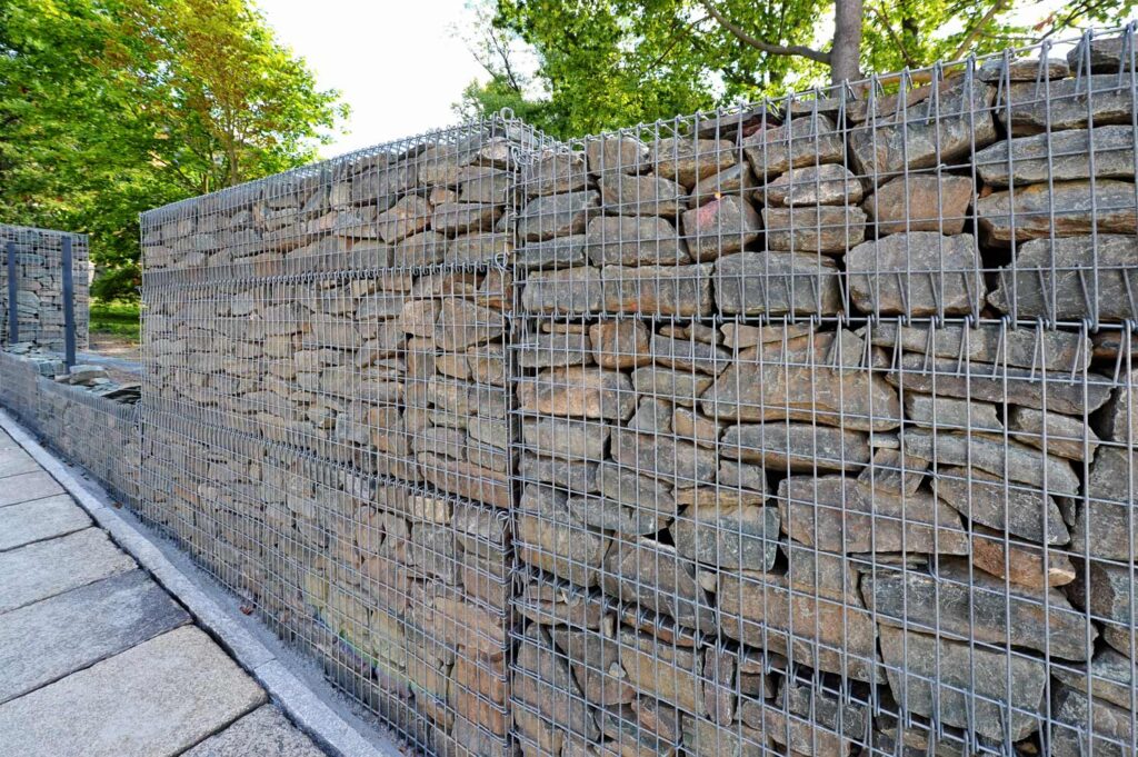 Eine lange Gabionenwand mit Natursteinfüllung als Stützelement oder Abgrenzung.