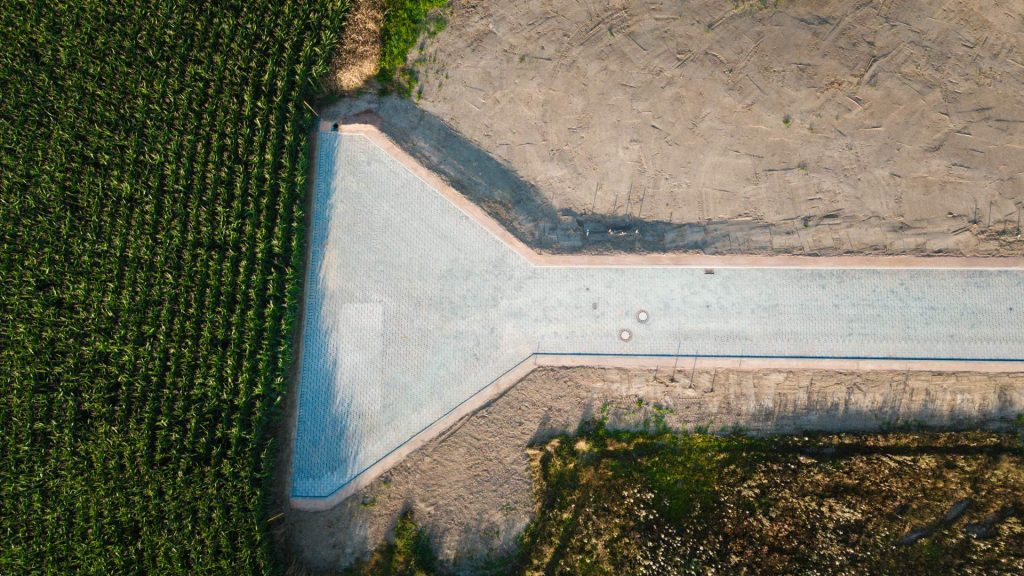 Luftaufnahme der fertig gepflasterten Straße im Wohngebiet Theuma, die die bis zum rand eines Feldes reicht. 