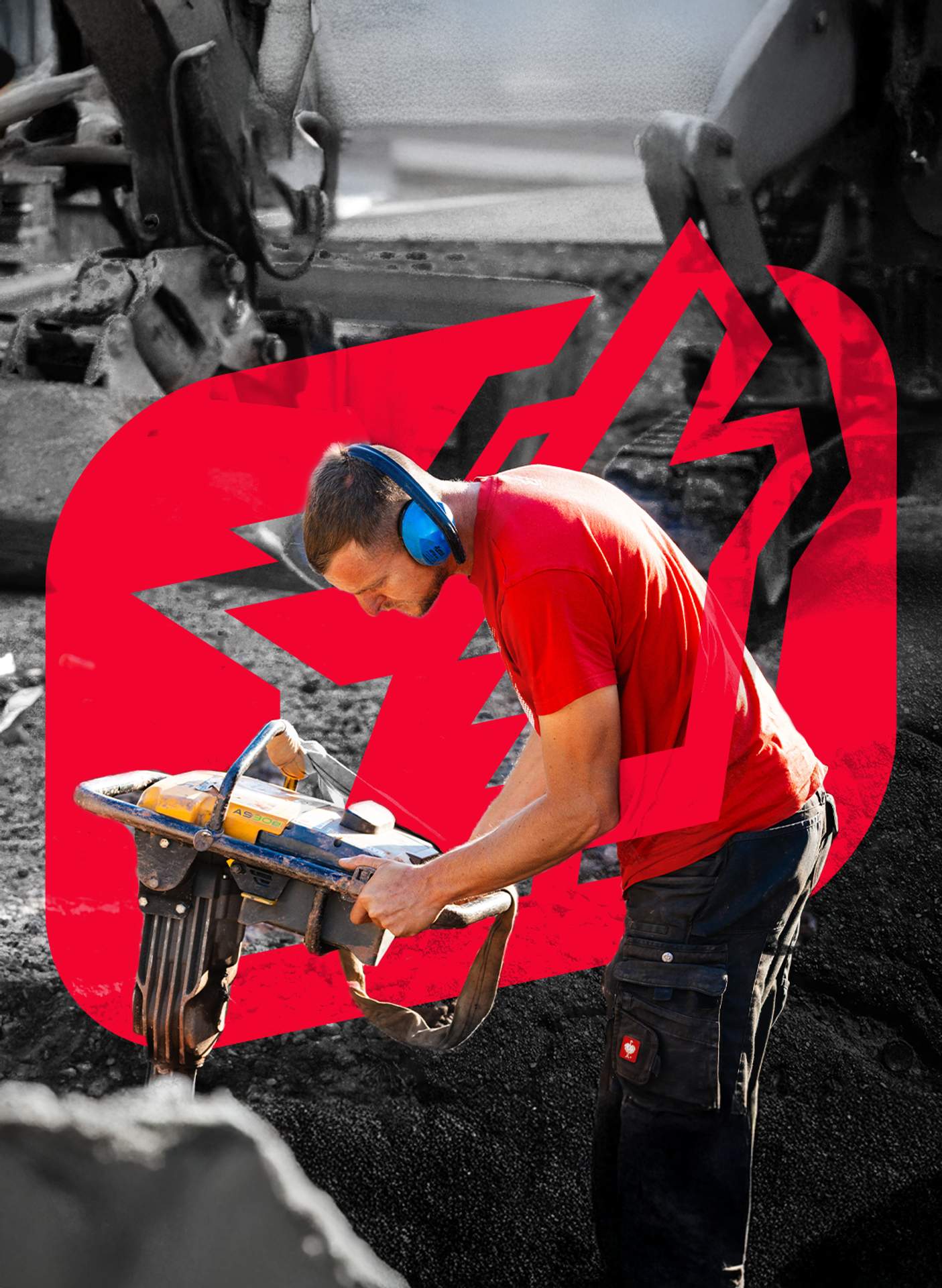 Ein Arbeiter mit Gehörschutz und einem roten T-Shirt bedient einen Stampfer auf einer Baustelle.