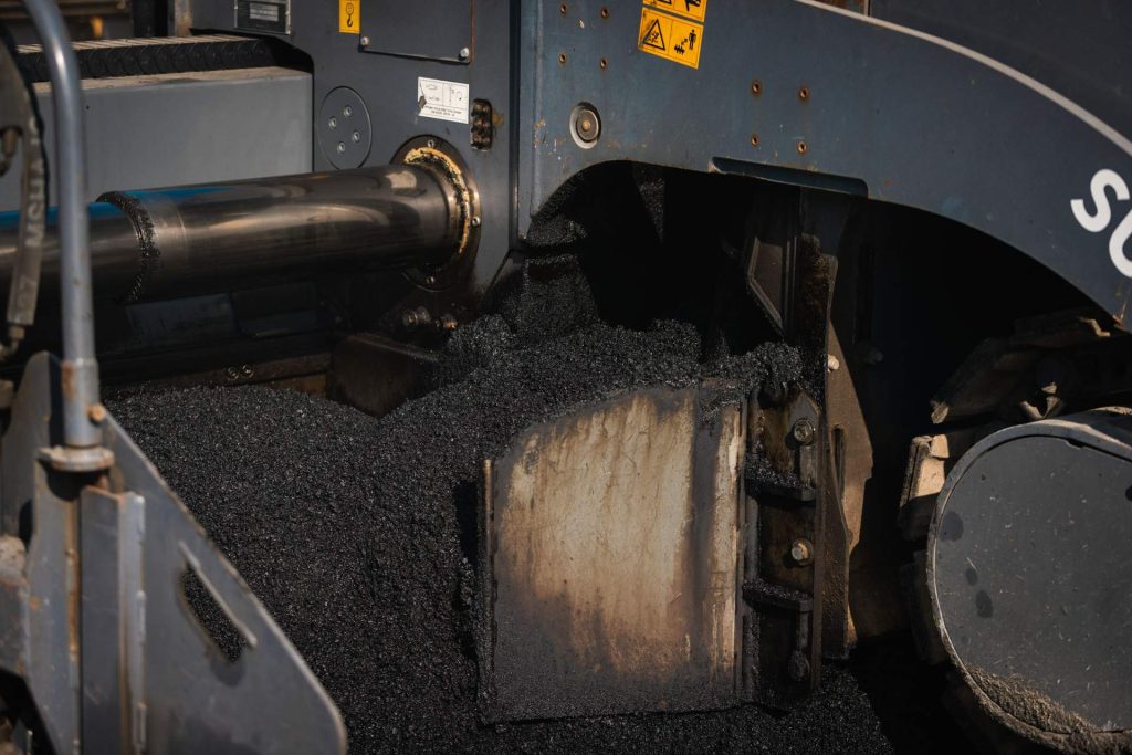 Straßenfertiger mit Asphaltmischung in Nahaufnhme