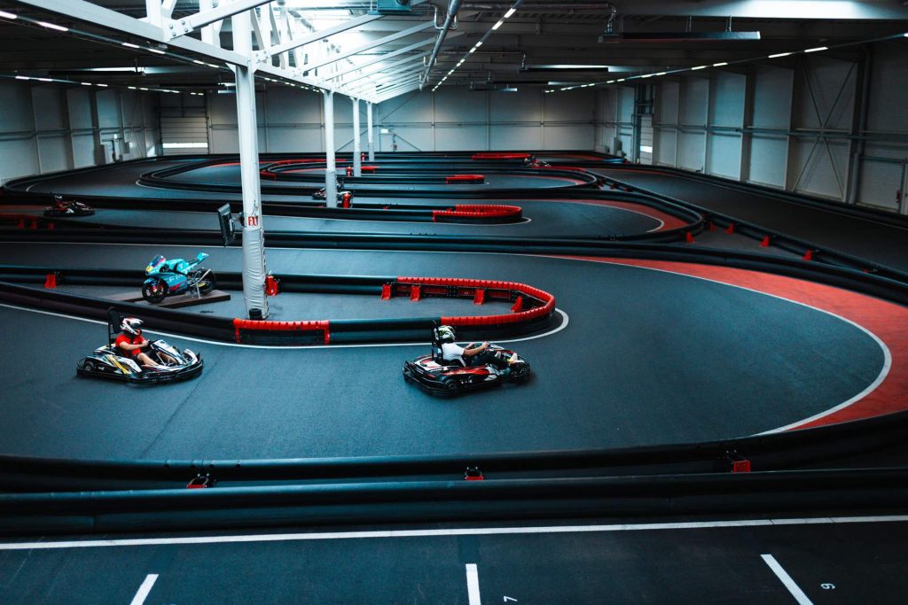 Indoor-karthalle der Arena E von oben fotografiert, mehrere Fahrer auf der Strecke