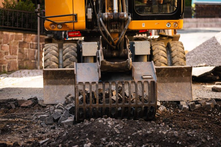 Baggerfahrer arbeitet auf Baustelle neben verlegten Rohren.