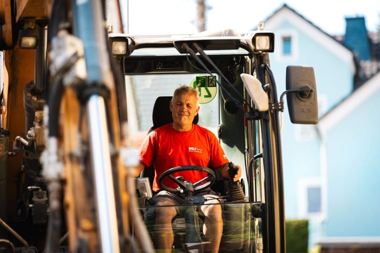 Nahaufnahme eines zufriedenen Baggerfahrers in der Kabine, wirbt für Stellenangebote bei Wolf.