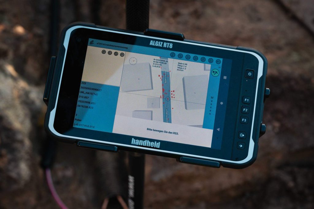 Nahaufnahme eines robusten ALGIZ RT8 Tablets, das einen digitalen Bauplan und Vermessungsdaten auf einer Handheld-Stange anzeigt.