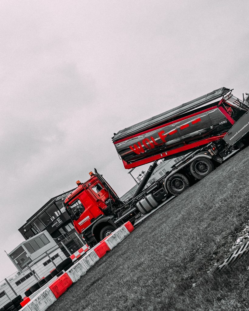Baustellenlogistik für den Rennsport: Schräge Ansicht eines Wolf-Kippers beim Materialtransport an der Outdoor-Kartstrecke.
