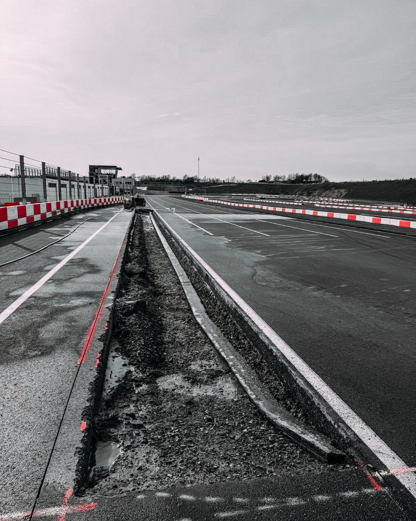 Tiefbau an der Rennstrecke: Geöffnete Fahrbahndecke für Kurvenanpassungen und neue Entwässerungsrinnen in der Arena E.